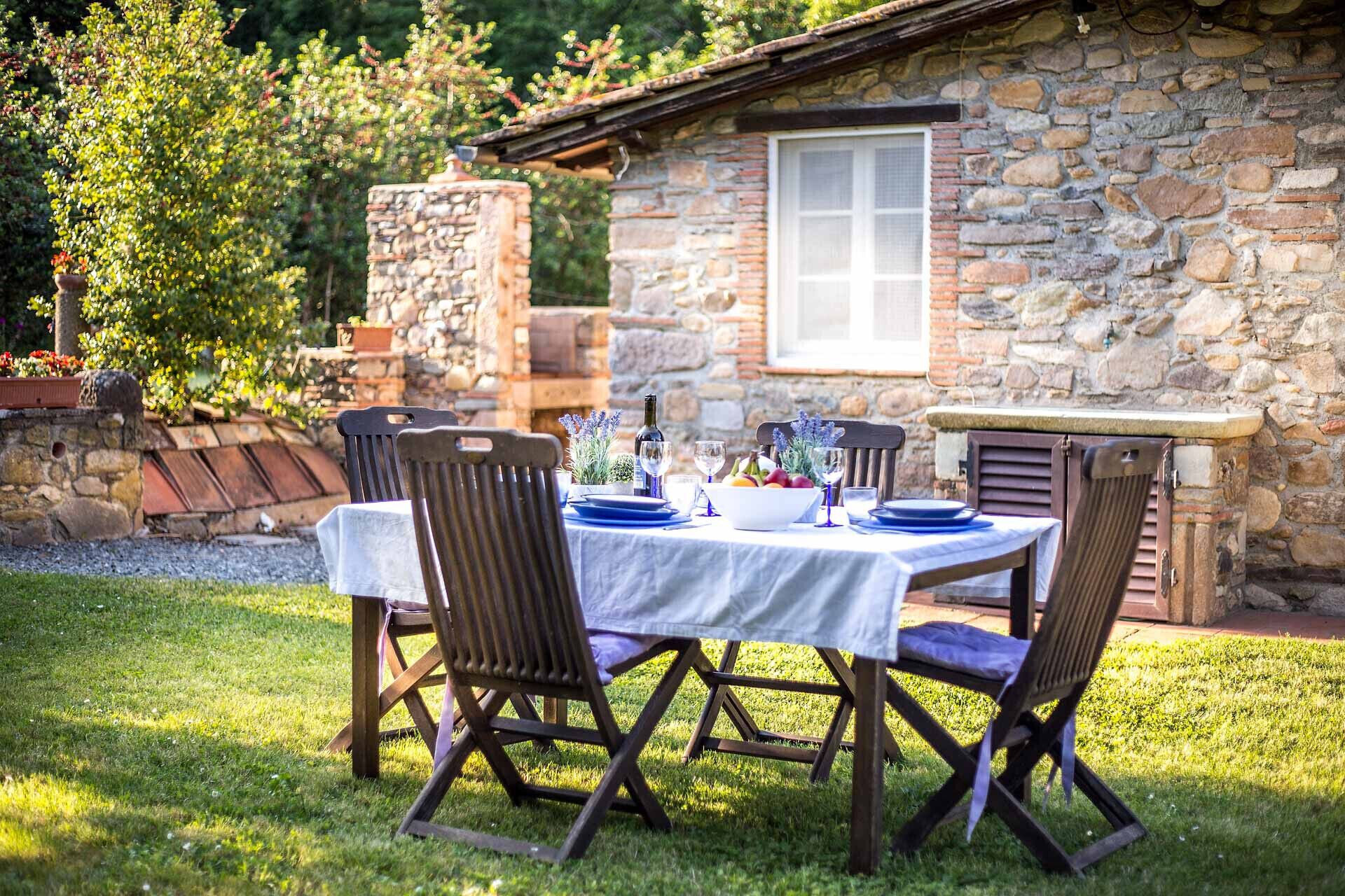 A stone building with a window and a table set for dining outdoors.
