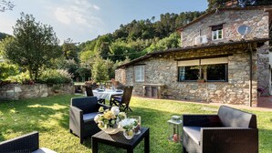 A stone house with a patio area featuring wicker furniture and a table set for dining. - A secret sweet idyllic retreat for 2 couples with private pool & air conditionin (Pieve di Compito)