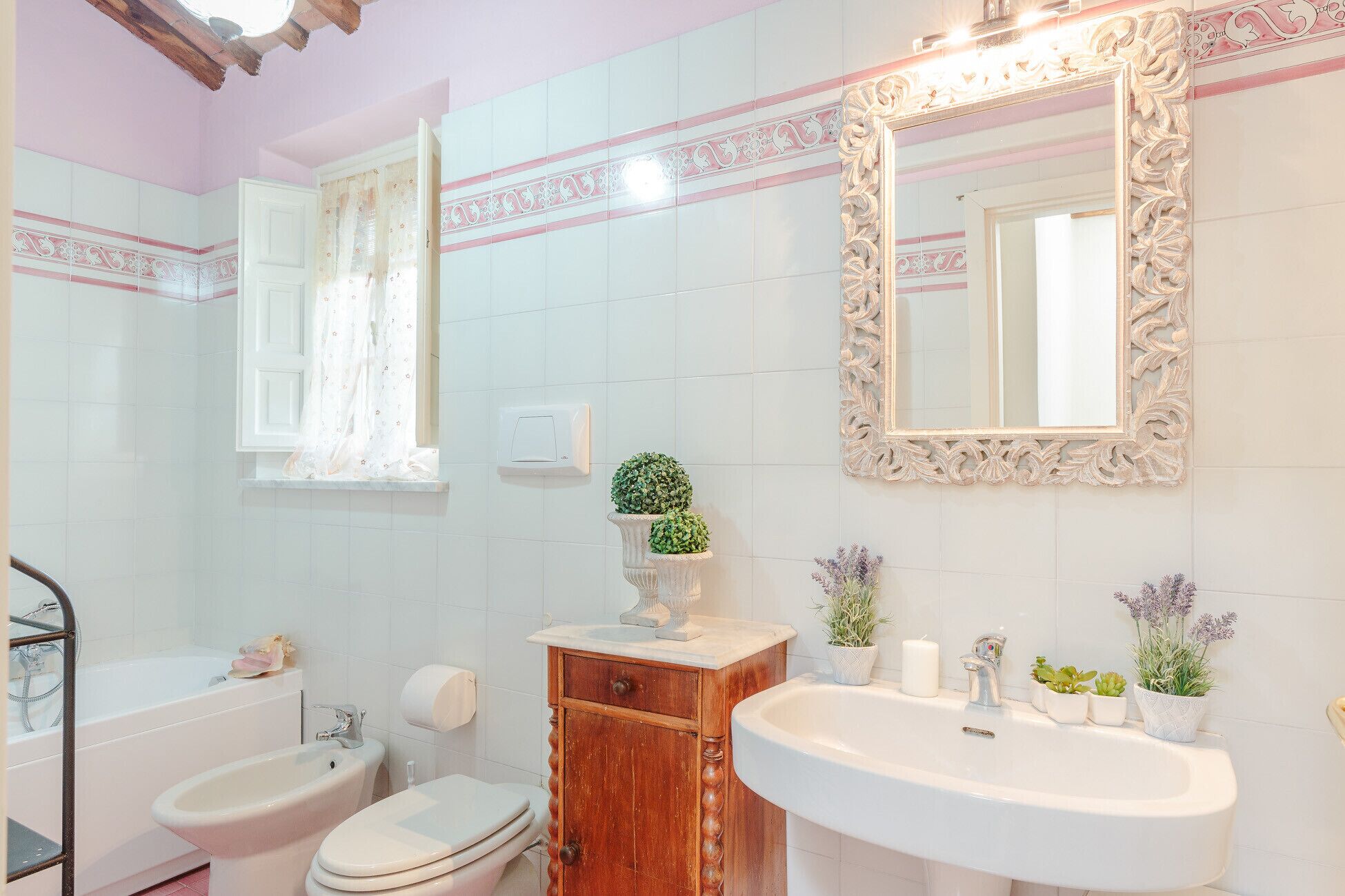 A bathroom with a vanity, sink, two toilets, and a bathtub.