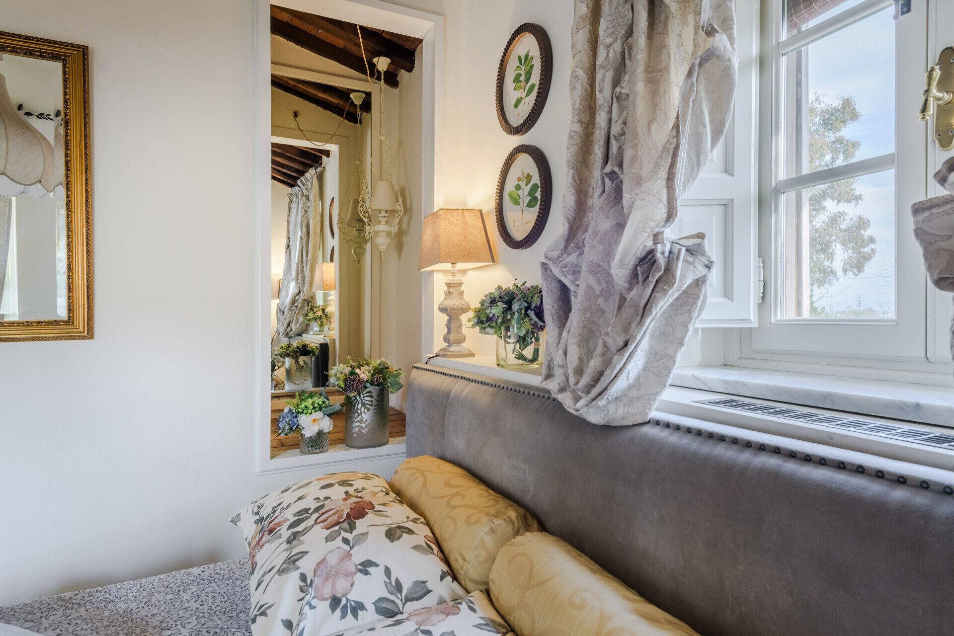 Une pièce confortable avec un canapé, une fenêtre avec des rideaux, une lampe et des éléments de décoration murale.