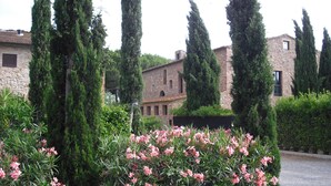 A stone building with a garden in front, surrounded by tall trees.