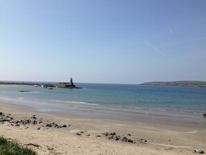 A beach with a lighthouse, calm water, and a distant hill. - Luxury Cottage in a Scottish Coastal location with view over rolling countryside (Stranraer)