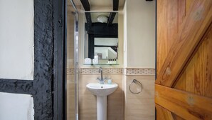 Ein Badezimmer mit Waschbecken, Spiegel und Holztür.