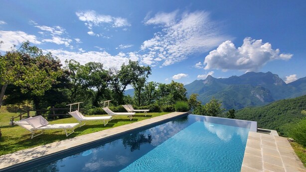 Una piscina con sillones de descanso y vistas a montañas.