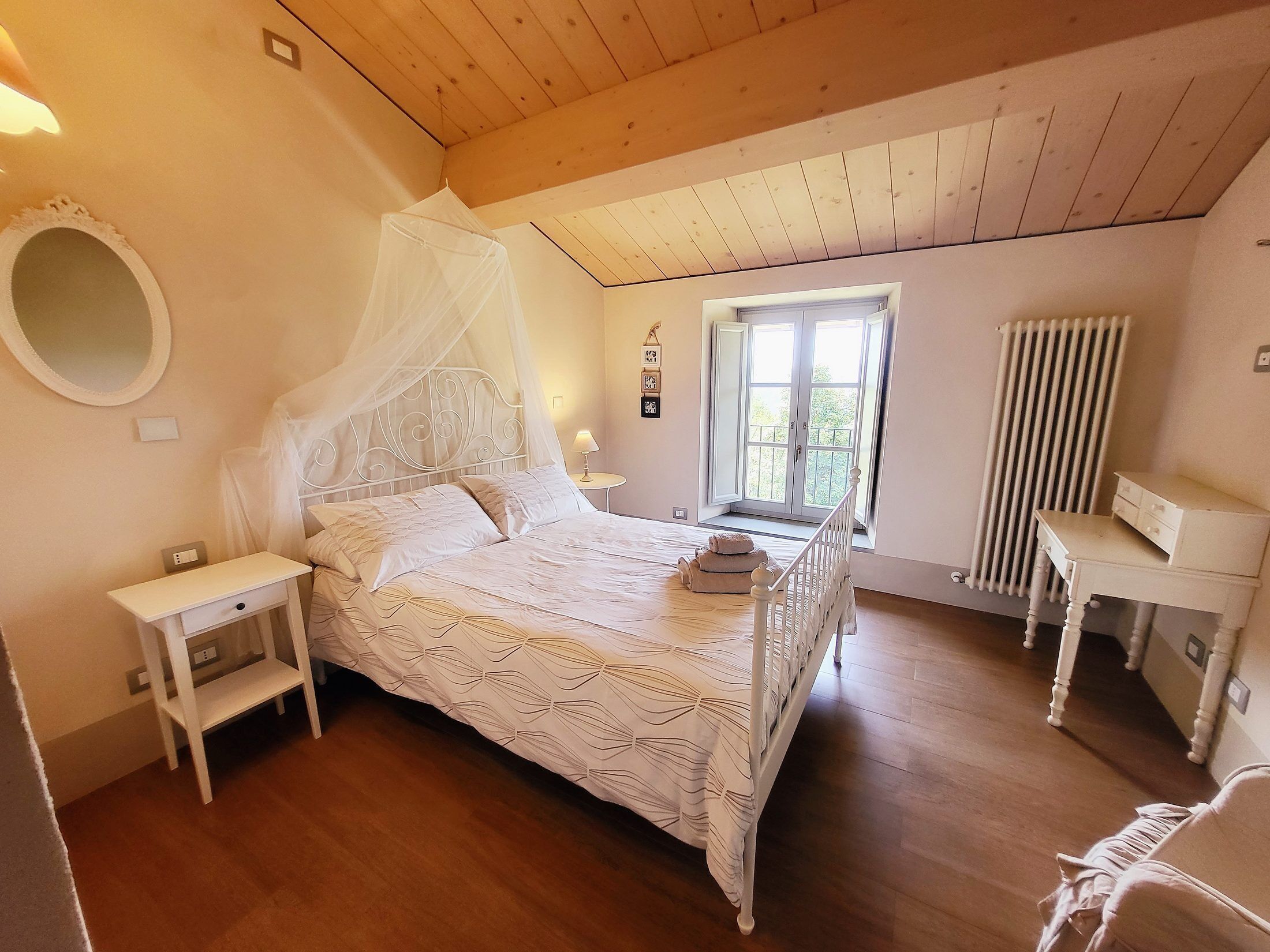 Une chambre à coucher comprenant un lit, des tables de chevet, un bureau, une chaise, une fenêtre et un radiateur.