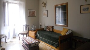Una habitació acollidora amb un llit, una cadira, una taula i una finestra amb cortines.
