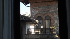 Edifici tradicional amb façana de pedra, finestres arquejades i un balcó amb plantes en testos.