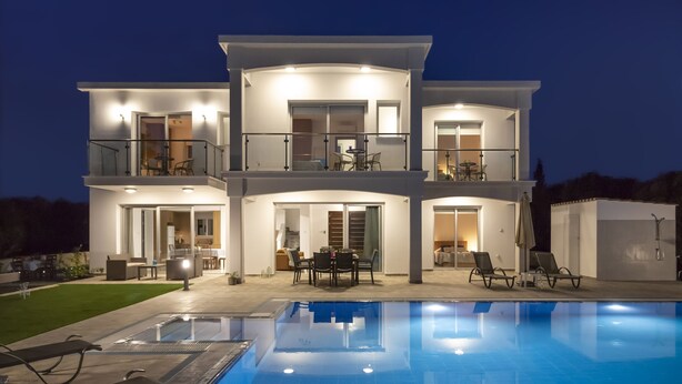 A modern two-story house with a swimming pool, outdoor seating, and a covered patio.