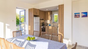 A modern kitchen with wooden cabinets, a refrigerator, and a dining area with a table set for four.