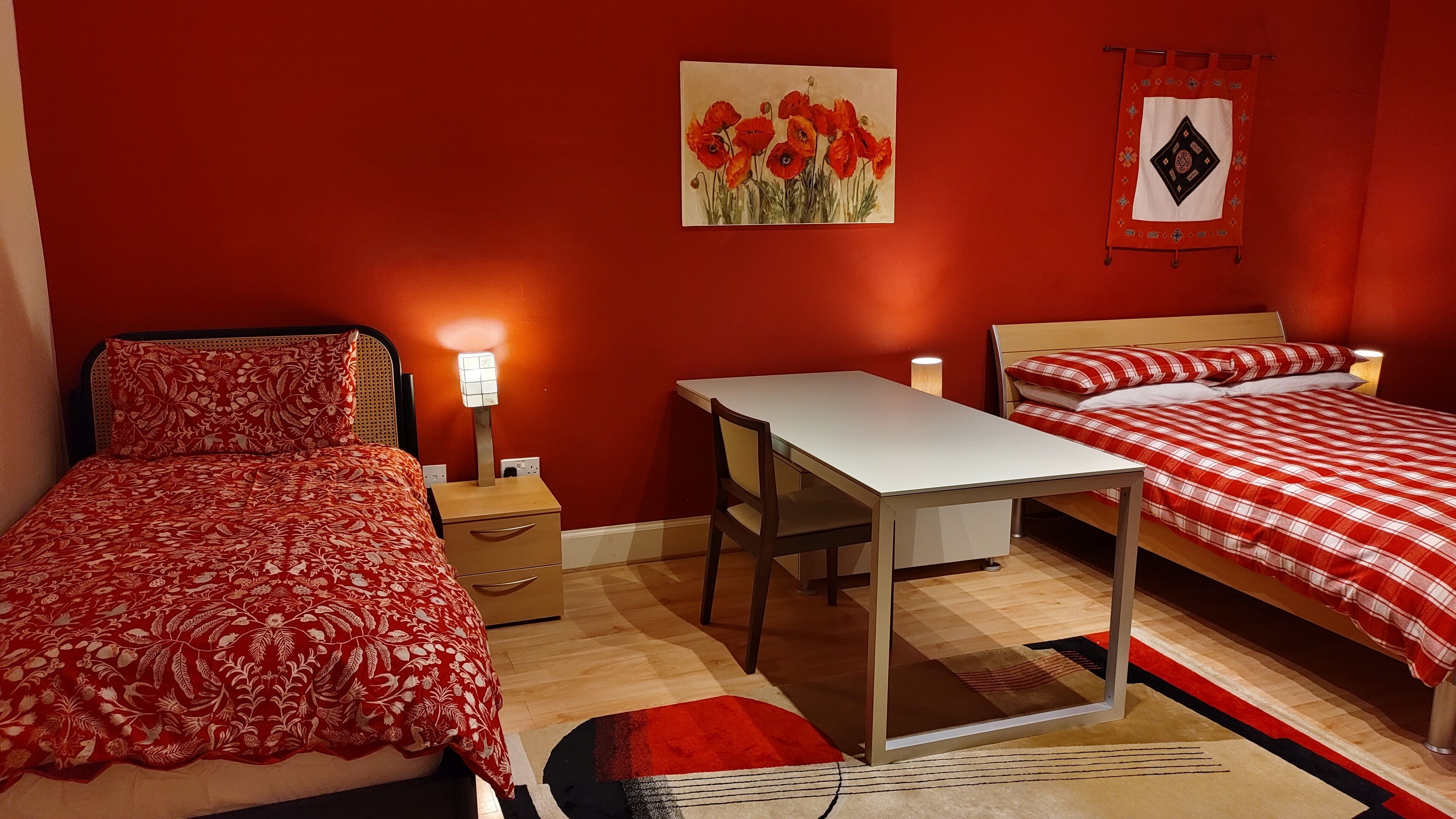 Une chambre avec deux lits, un bureau et une table de chevet avec une lampe.