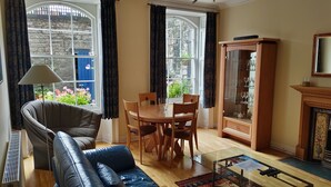 A room with a leather sofa, a dining table with chairs, a glass cabinet, and a fireplace. - Stylish Apartment in Edinburgh City Centre, Sleeps 4. License no. EH-68704-F (Edinburgh)