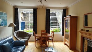 A room with a leather sofa, a dining table with chairs, a cabinet, and a fireplace. - Stylish Apartment in Edinburgh City Centre, Sleeps 4. License no. EH-68704-F (Edinburgh)