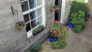 A courtyard with potted plants, a wooden bench, and a stone wall. - Stylish Apartment in Edinburgh City Centre, Sleeps 4. License no. EH-68704-F (Edinburgh)