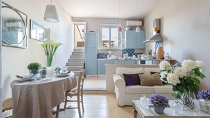 A cozy living room with a dining area, a staircase leading to a kitchen, and a view of the outside. - CASA MARGHERITA Stunning view from Terrace (Lucca)