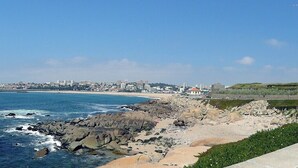 A coastal cityscape with a rocky shoreline, a sandy beach, and a distant city skyline. - Beach front apartment with superb sea view, 10 min. from Porto   (Vila Nova de Gaia)