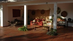 A covered outdoor seating area with a wooden floor, a sofa, and a dining table. - Azeitao: Holidays Villa with pool and beach nearby (Azeitão)