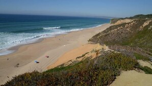 A beach with a sandy shore, a wooden walkway, and a clear view of the ocean. - Azeitao: Holidays Villa with pool and beach nearby (Azeitão)