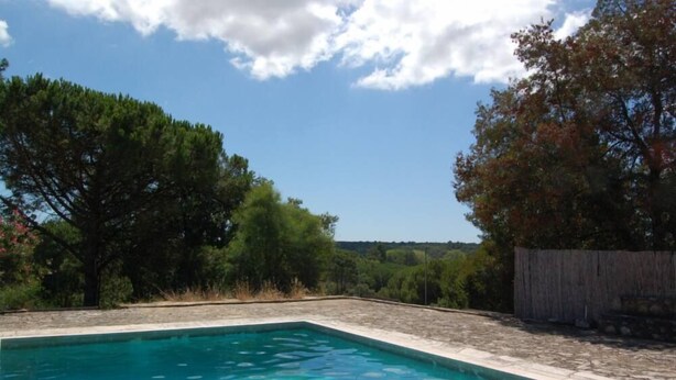 A rectangular swimming pool with clear blue water, surrounded by a stone deck and a wooden fence. - Azeitao: Holidays Villa with pool and beach nearby (Azeitão)