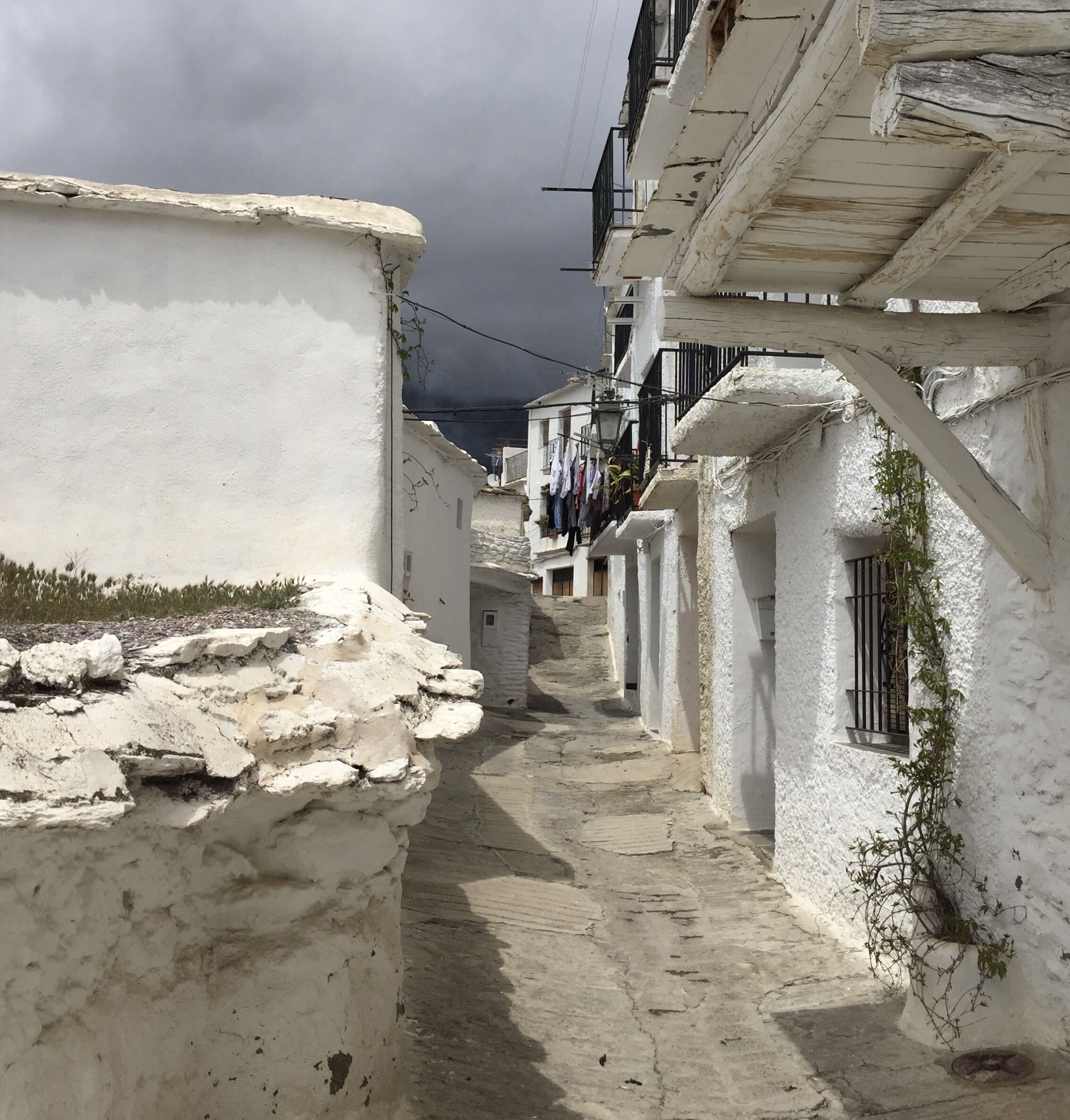A narrow, white-walled alley with stone steps leading to a building.