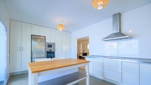 Une cuisine moderne avec des meubles blancs, une table en bois et des appareils électroménagers intégrés.