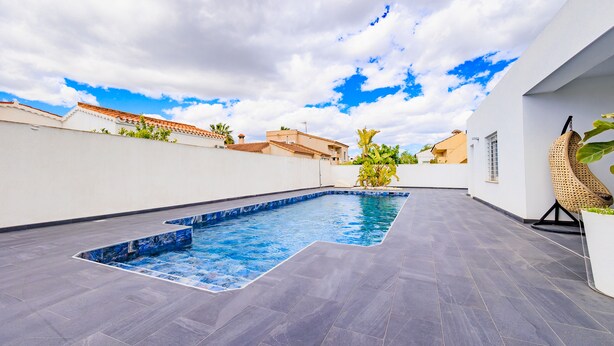 Une piscine sur le toit, dotée d’une terrasse carrelée, entourée de murs blancs et surplombant un ciel dégagé.