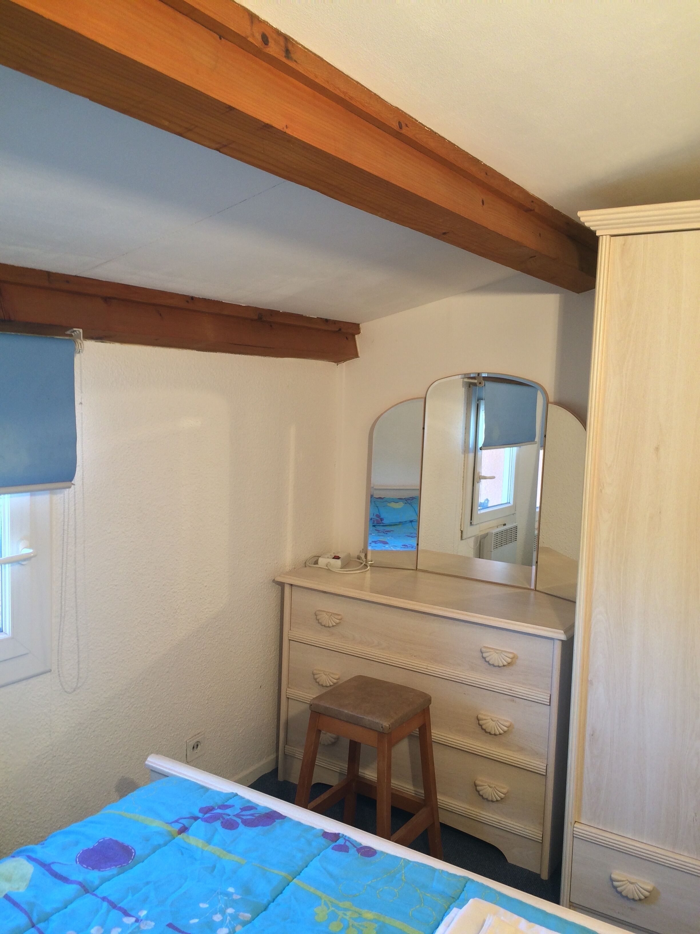 A bedroom with a bed, a dresser, a mirror, and a window.