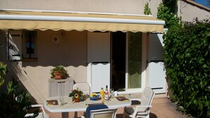 A covered patio with a table set for two, a potted plant, and a satellite dish on the building. - Family friendly villa only 5 minutes walk to the Cap d'Agde beach (Richelieu) (Agde)