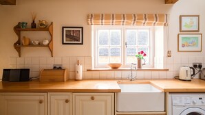 A kitchen with a wooden countertop, a sink, a washing machine, and a window with a view of the outside. - Boddingtons Barn in the Cotswolds  (1 Bedroom) (Gloucestershire)