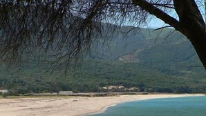Une plage à l’eau claire et au rivage sablonneux, entourée de collines.
