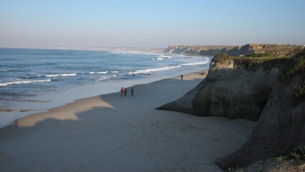 Ein Strand mit einer felsigen Klippe und Meereswellen.
