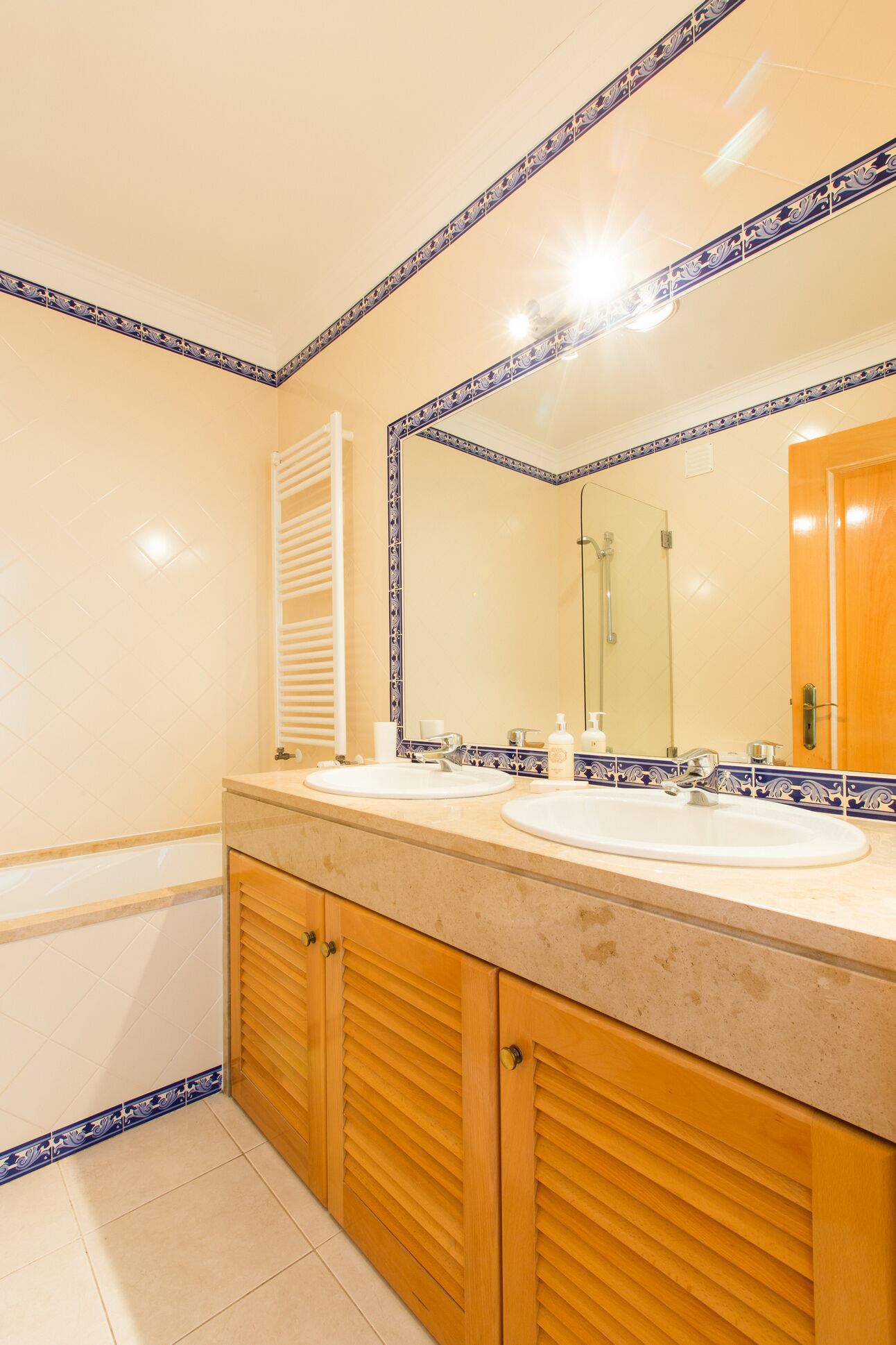 Un bagno con due lavandini, uno specchio grande e mobili in legno.