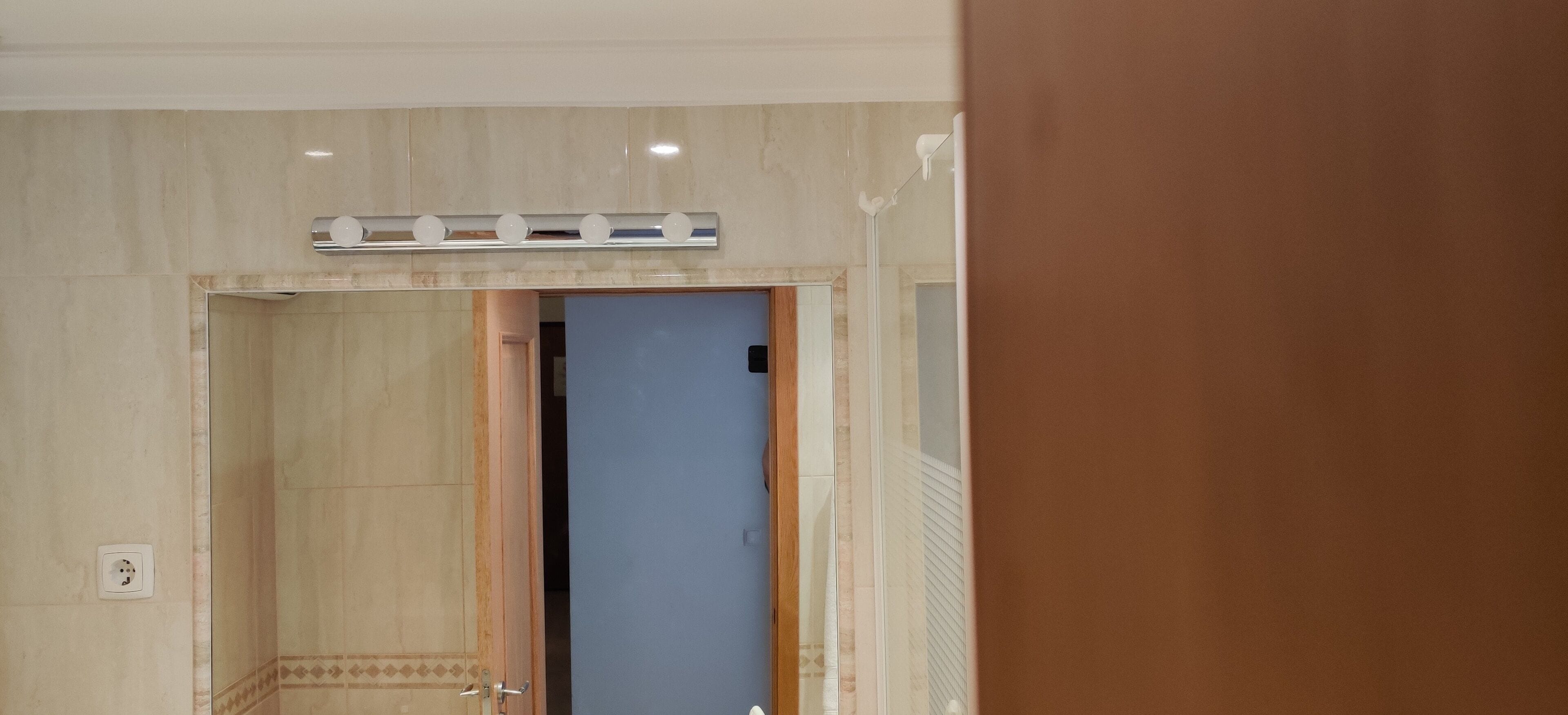 Ein Innenraum einer Hotelzimmere mit einer Badezimmertür, einem Spiegel und einer Leuchte darüber.