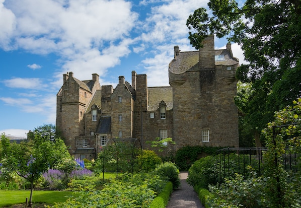 A historic stone castle with multiple towers and a well-maintained garden.