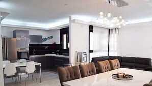 A modern kitchen with a 'Kitchen' sign, a dining area with a white table and brown chairs, and a black leather sofa. - ☆ Sublime apartment in the heart of Jerusalem ☆ (Jerusalem)