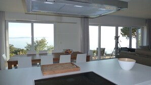 Een moderne keuken met een centraal eiland, grote ramen en uitzicht op de omgeving.