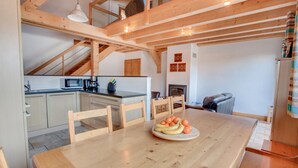 A wooden dining table with a fruit platter, a kitchen area with a microwave, and a staircase leading to an upper level. - Modern 4 bed Chalet, Hot tub, Stunning views of Morzine, easy access to Avoriaz (Morzine)