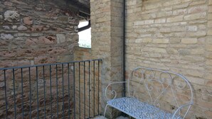 A metal bench against a stone wall with a metal fence. - Attic in the center of Assisi (Assisi)