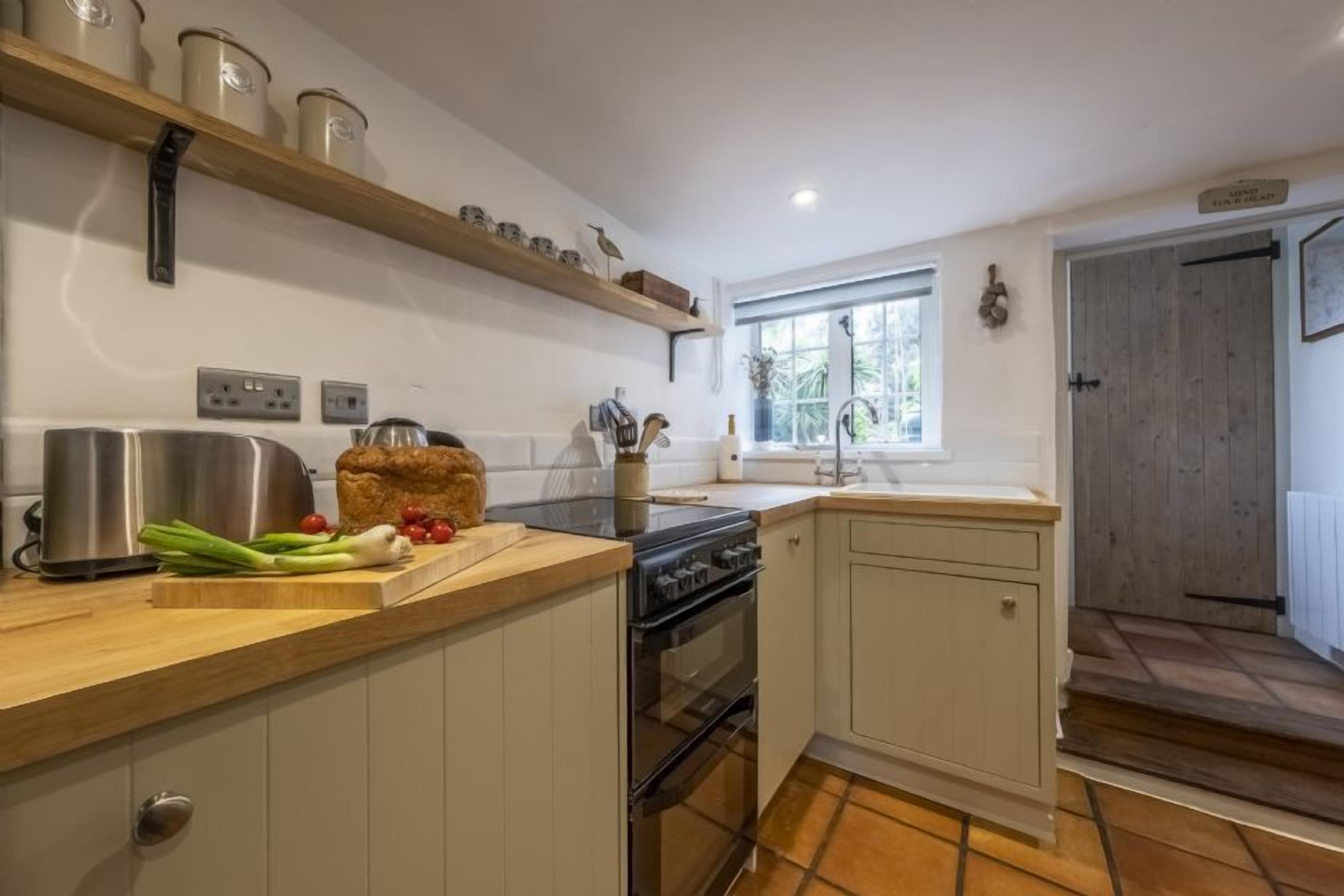 A kitchen with a wooden countertop, stainless steel appliances, and a window.