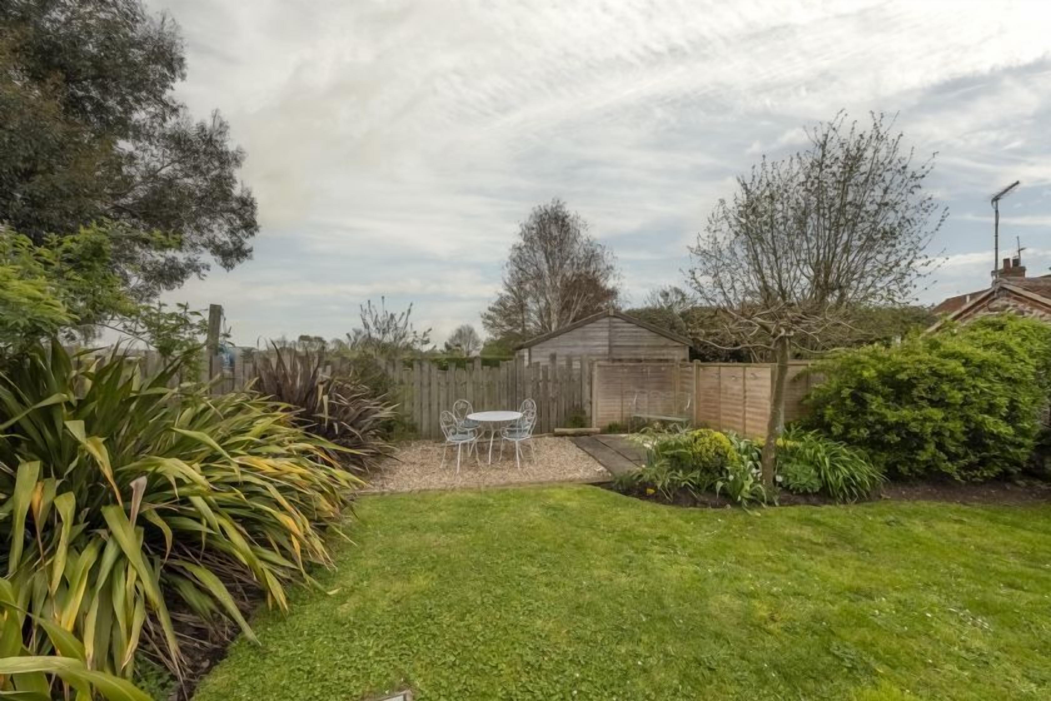 A backyard with a wooden fence, a small shed, and a table with chairs.