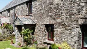 A stone building with a traditional design, featuring multiple windows and a small porch area. - Spacious Cottage With Sea Views (Trevillett)