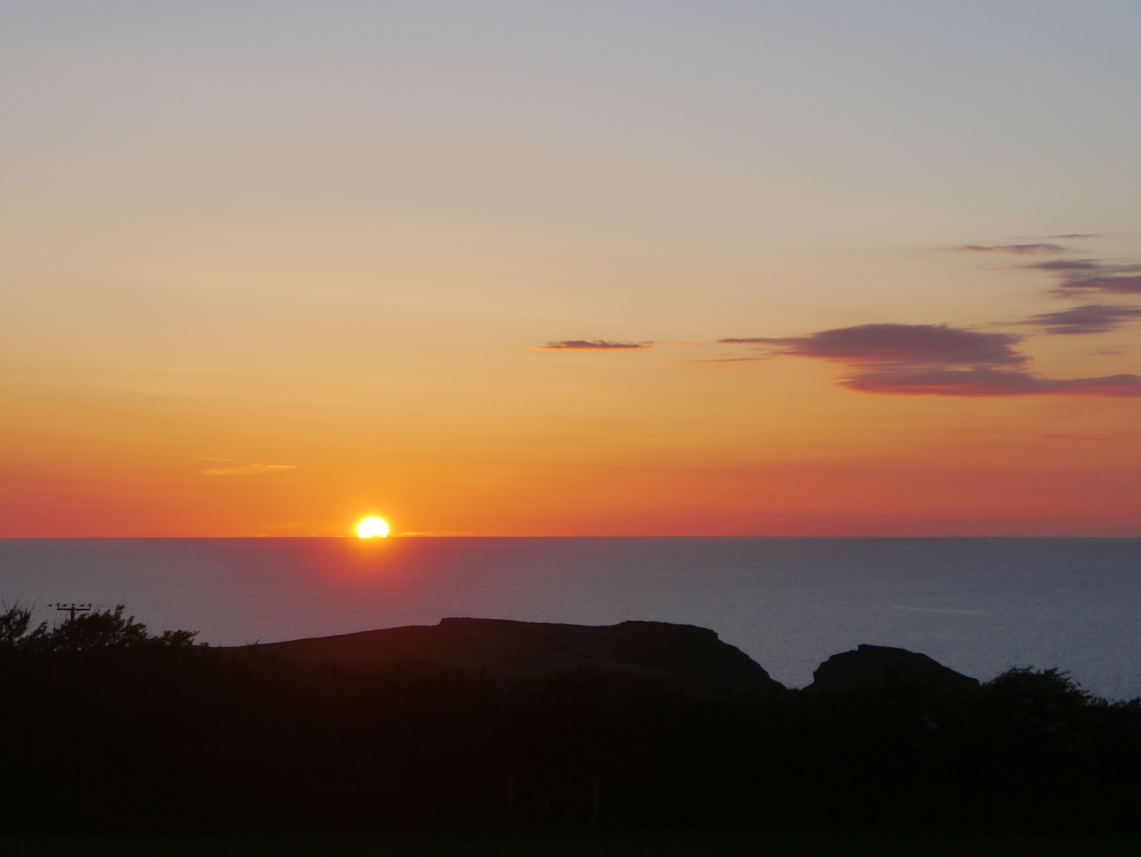 Un atardecer sobre un paisaje costero con afloramientos rocosos.