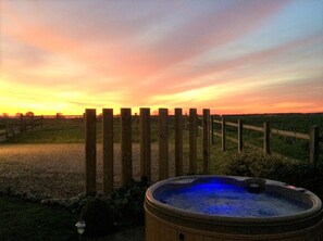 A hot tub with a wooden fence in the background during sunset.
