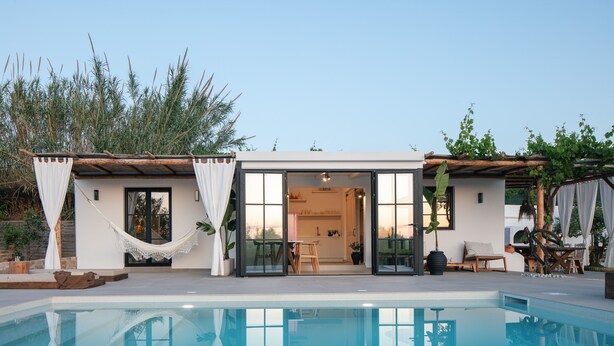 A modern house with a pool, featuring a glass door entrance, a hammock, and a patio area with outdoor furniture. - Walking Distance to Platanias Centre and the Beach! Heated pool! (Chania)