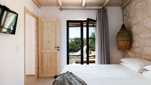 A bedroom with a bed, a wooden door, a television, and a view of an outdoor area with a pool and lounge chairs. - Walking Distance to Platanias Centre and the Beach! Heated pool! (Chania)