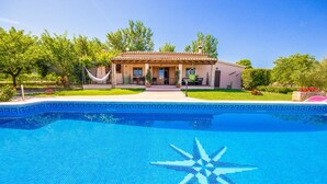 Ein Swimmingpool mit Sternen-Mosaik, umgeben von einem Haus mit einem Ziegeldach und einem Garten.