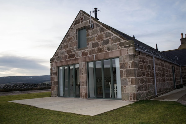 A stone building with large glass doors and a sloped roof.