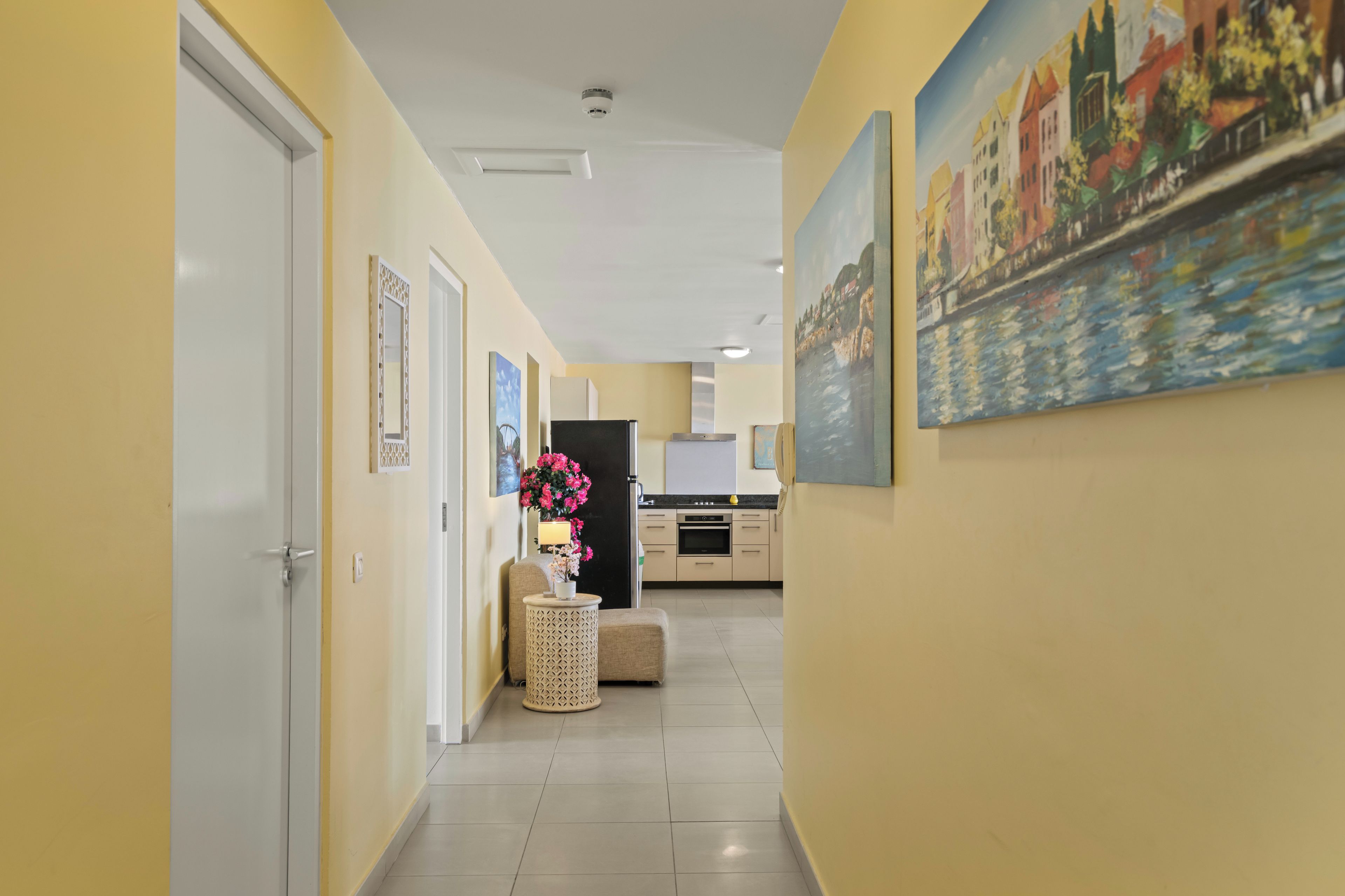Corredor com área de cozinha, com geladeira, forno e armários.