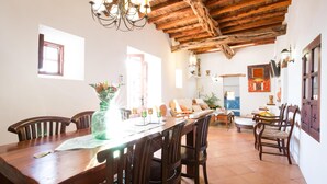 Un coin repas avec une table et des chaises en bois, un lustre et une vue sur le salon.