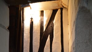 Eine Wendeltreppe mit Holzstufen und schwarzen Geländern, die in einem schmalen Raum nach oben führt.