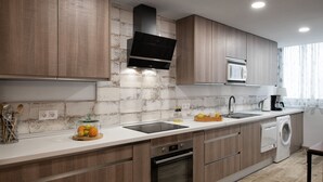 Une cuisine moderne avec des meubles en bois, un four encastré, un four à micro-ondes et un lave-linge.